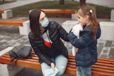 Tek kullanımlık maskeli bir kadın çocuğuna solunum cihazı takmayı öğretiyor.