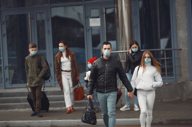 Havaalanından ayrılan gezginler koruyucu maskeler takıyorlar.