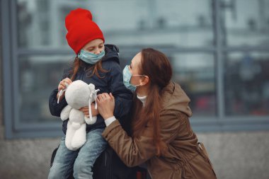 Kızıyla birlikte solunum cihazına bağlı Avrupalı bir anne binanın yanında duruyor. Ebeveyn kendini virüsten korumak için çocuğuna koruyucu maske takmayı öğretiyor.