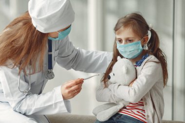Doktor ve koruyucu maskeli bir çocuk hastanedeler.