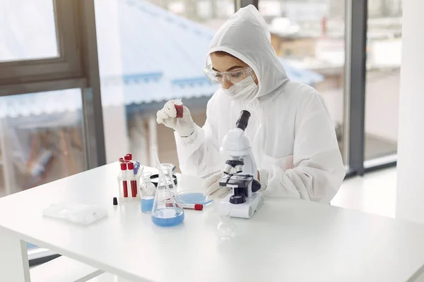 Работник лаборатории в защитном костюме настраивает микроскоп — стоковое фото
