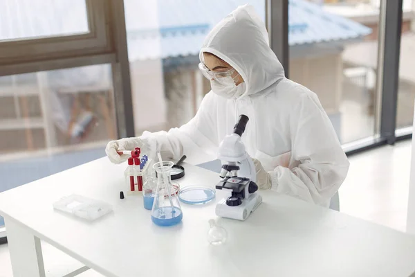 Работник лаборатории в защитном костюме настраивает микроскоп — стоковое фото