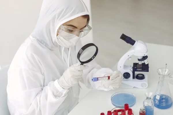 Wetenschapper in coverall kleding onderzoekt coronavirus monster in een laboratorium — Stockfoto