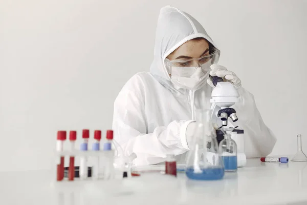 Bir laboratuvar bilimcisi mavi çözeltiyi şişede inceliyor.