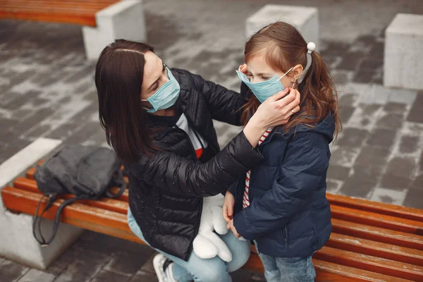 Tek kullanımlık maskeli bir kadın çocuğuna solunum cihazı takmayı öğretiyor.