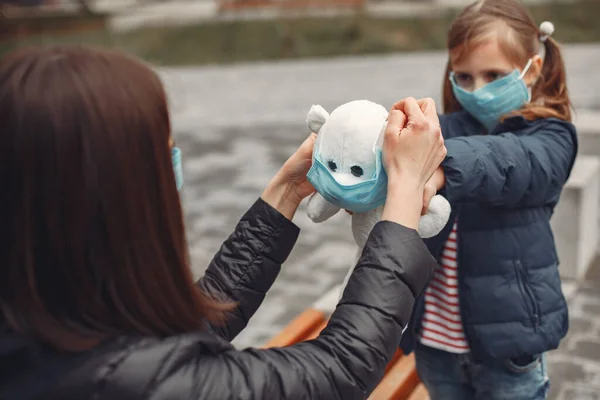 Woman in a disposable mask is teaching her child to wear a respirator — Stock Photo, Image