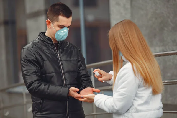 Unga människor som bär skyddsmasker sprutar handdesinfektionsmedel — Stockfoto