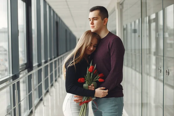 Couple européen est debout dans un hall avec un tas de tulipes rouges — Photo