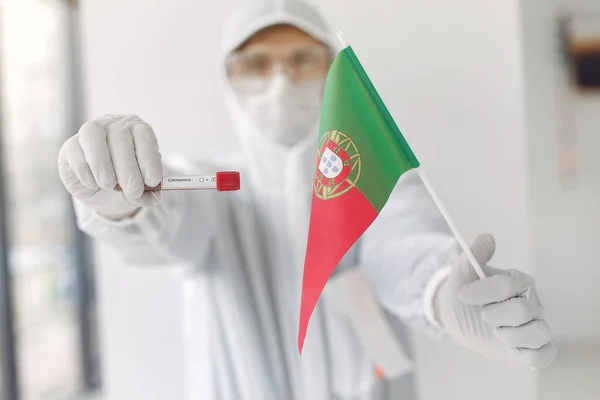 Ученый в комбинезоне с образцом коронавируса и португальским флагом Лицензионные Стоковые Фото