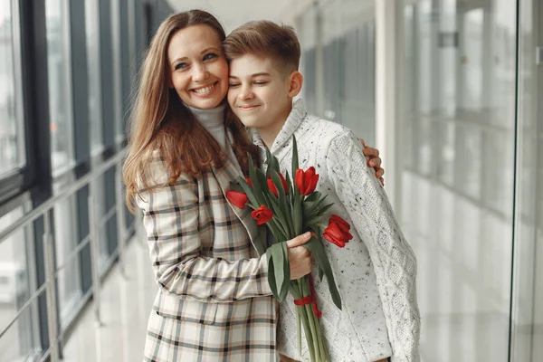 Сын дарит матери кучу красных тюльпанов в amodern Hall Лицензионные Стоковые Фото