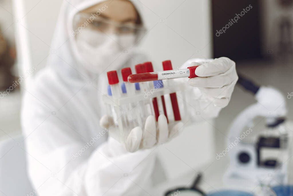 Scientist in special equipment is showing coronavirus testing sample