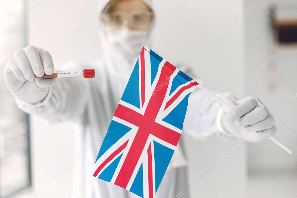 The scientist in coverall suit with a coronavirus sample and British flag