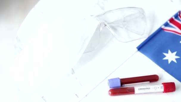 Muestra de pruebas de coronavirus y bandera australiana están sobre la mesa — Vídeo de stock