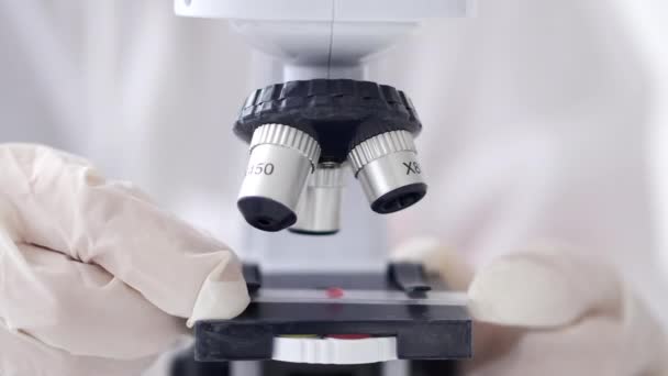 Onderzoeker past een microscoop aan in een laboratorium — Stockvideo