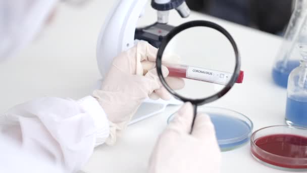Científico está examinando la muestra de coronavirus en un laboratorio — Vídeos de Stock