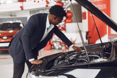 Yakışıklı ve zarif bir siyah adam bir araba salonunda.