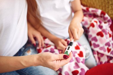 Anne, hasta kızının ateşini ölçüyor.