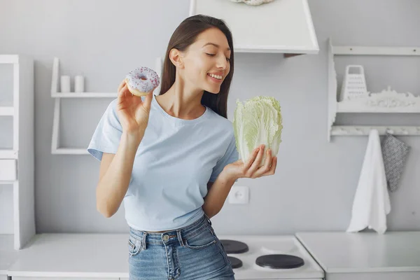 Menina bonita de pé em uma cozinha com donut — Fotografia de Stock