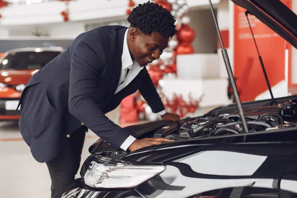 Hombre negro guapo y elegante en un salón de coches —  Fotos de Stock