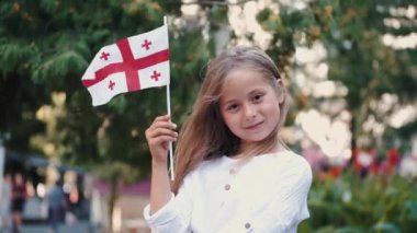 Elinde Gürcü bayrağı tutan küçük kız dışarıda duruyor.