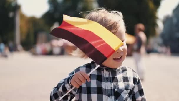Маленький мальчик, двигающий немецкий флаг в центре города — стоковое видео