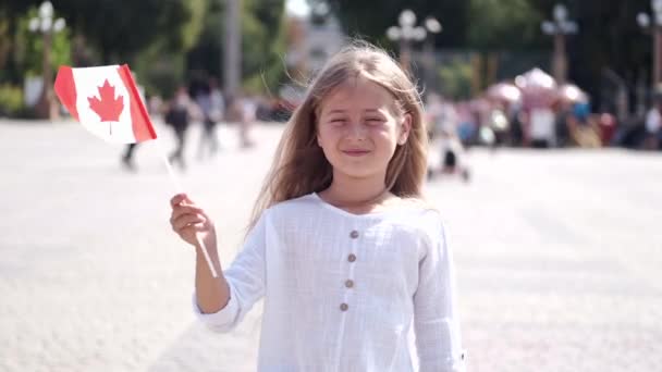 Blond girl standing on square holding Canadian flag — Stock Video