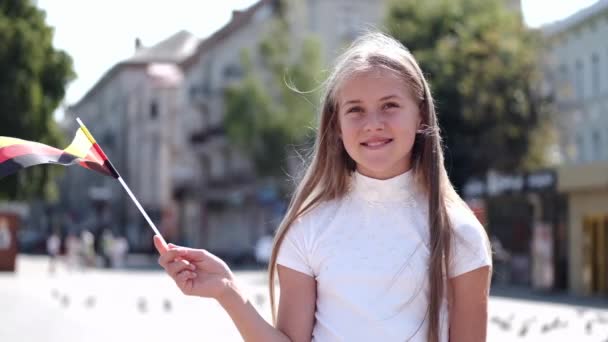 Девушка, стоящая на площади с немецким флагом летом — стоковое видео
