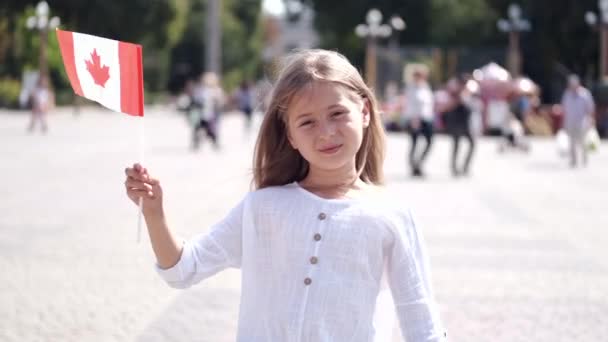 Menina loira de pé na praça segurando bandeira canadense — Vídeo de Stock