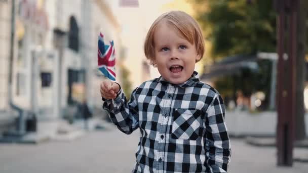 Malý chlapec s blond vlasy drží britskou vlajku — Stock video