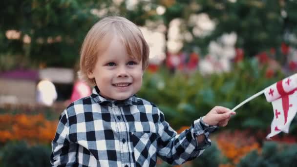 Little boy in checkered shirt holding Georgian flag — Stock Video