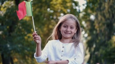 Parkta elinde İtalyan bayrağı tutan gülümseyen kızın portresi