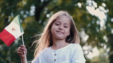 Parkta elinde İtalyan bayrağı tutan gülümseyen kızın portresi