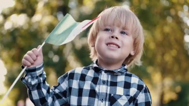 Blonďatý chlapec v kostkované košili drží italskou vlajku — Stock video