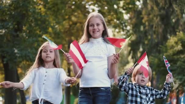 Barn med flaggor tillbringar tid utomhus i parken — Stockvideo