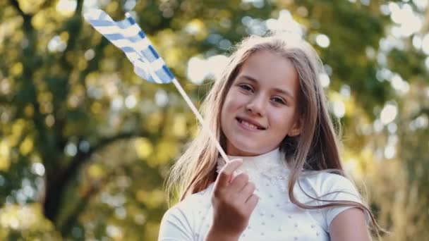 笑顔の女の子の肖像公園でギリシャ語のフラグを保持 — ストック動画