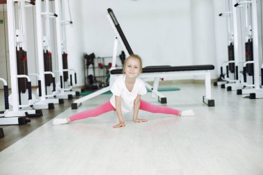 Küçük tatlı kız spor salonunda jimnastik yapıyor.