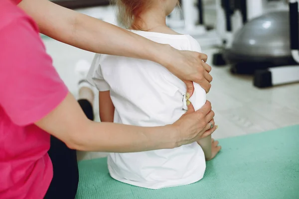 Mãe com pequena filha está envolvida em ginástica no ginásio — Fotografia de Stock