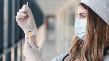 Tıbbi eldivenli hemşire sarı solüsyonlu şırıngayı test ediyor.