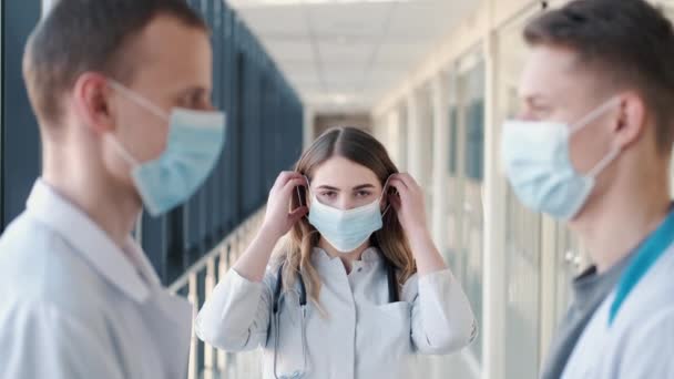 Artsen in gewaden delen wegwerpmaskers en doen ze op gezichten. — Stockvideo