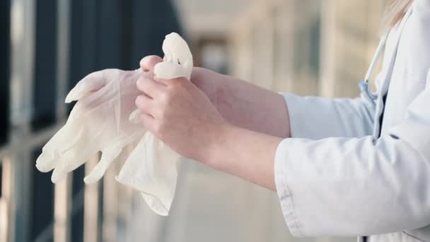 A nurse in a respirator is putting disposable rubber white gloves — Stock Video