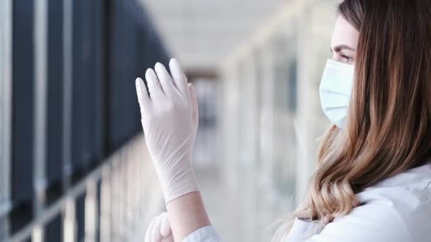 Медсестра в респіраторі кладе одноразові гумові білі рукавички — стокове відео