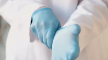 Bornozlu doktor mavi eldiven takıyor.