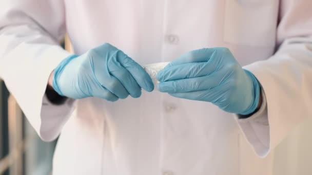 Doktor v županu a lékařských rukavicích vybaluje novou injekční stříkačku — Stock video
