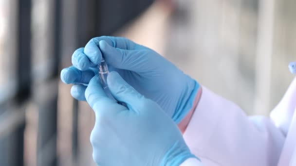 Γιατρός με ρόμπα και ιατρικά γάντια ξεπακετάρει νέο φιαλίδιο. — Αρχείο Βίντεο
