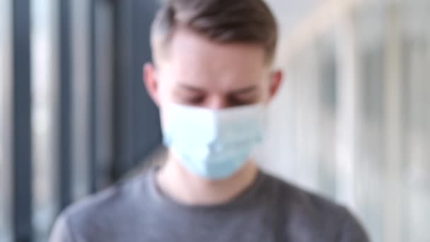 European serious boy in a mask is in a modern hall — Stock Video