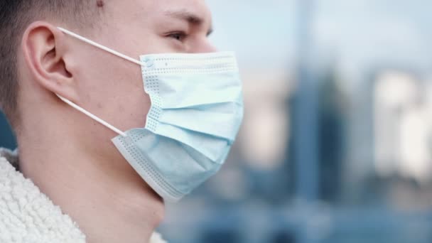 Een man niest en draagt een masker om zich te beschermen tegen het virus. — Stockvideo