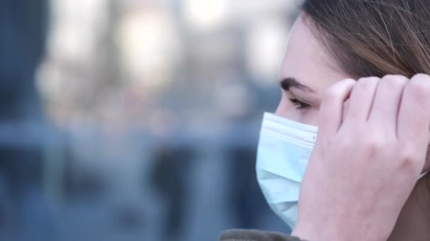 Jonge vrouw die buiten staat niest en draagt een wegwerpmasker — Stockvideo