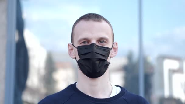 Een man niest en draagt een masker om zich te beschermen tegen het virus. — Stockvideo
