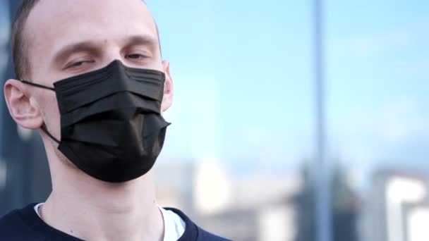 Een man niest en draagt een masker om zich te beschermen tegen het virus. — Stockvideo