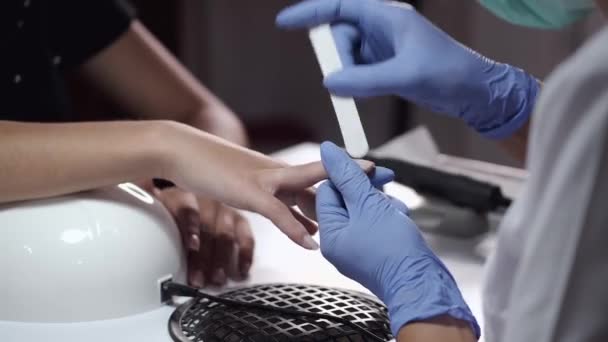 美容師の手のクローズアップは、女性のクライアントのためのマニキュアを作ります — ストック動画
